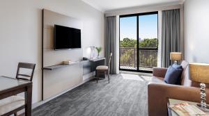 悉尼Oaks Sydney North Ryde Suites的带沙发和平面电视的客厅