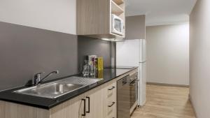悉尼Oaks Sydney North Ryde Suites的厨房配有水槽和冰箱