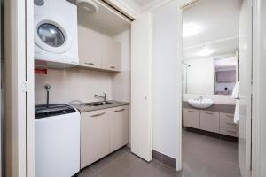 弗里曼特Fremantle Harbourside Luxury Apartments的白色的厨房配有水槽和洗衣机