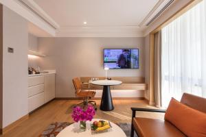 曼谷曼谷假日酒店的客厅配有桌子和墙上的电视