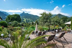 施伦斯Hotel Vitalquelle Montafon的一个带椅子和遮阳伞的庭院和山脉