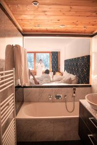 圣莫里茨圣莫里茨新吉安体育及康体酒店的带浴缸的浴室以及一张两人床。