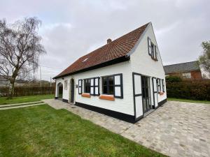 ZillebekeVakantiehuis Cas.tard的白色的房子,有黑窗和院子