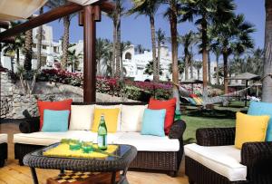 沙姆沙伊赫格兰罗塔纳度假村及Spa的一个带沙发和椅子的庭院,并种植了棕榈树。