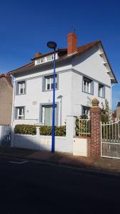 勒克罗图瓦Le Crotoy plage Baie de somme appartement l'Avocette的一条街上有蓝色柱子的白色房子