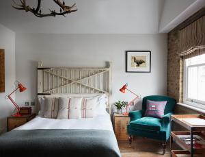 伦敦伦敦艺术家酒店的一间卧室配有一张床和一把绿色椅子
