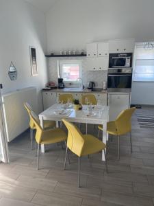 图赫尔斯克利普利采AQUA-TUHELJ- SKY的厨房配有白色的桌子和黄色的椅子