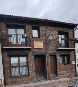 洛索亚河畔布伊特拉戈Puente viejo de Buitrago casa Enebro的砖砌建筑,设有窗户和阳台