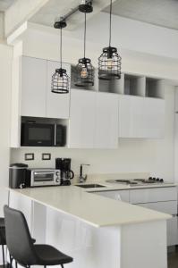 危地马拉Cozy Stays Cayala Apartments 4的厨房配有白色橱柜和黑色椅子
