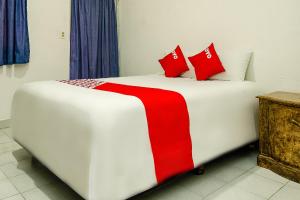 卡波圣卢卡斯OYO Hotel Cabo Del Sur, Cabo San Lucas的客房内的白色床和红色枕头