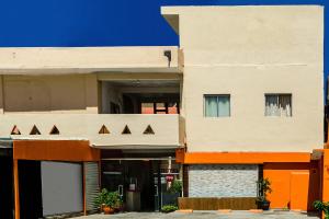 卡波圣卢卡斯OYO Hotel Cabo Del Sur, Cabo San Lucas的公寓大楼拥有橙色和白色的外墙