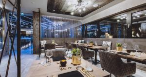 萨尔巴赫GLEMM by AvenidA Superior Hotel & Residences的餐厅设有木桌、椅子和窗户。