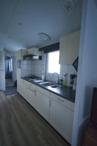 Hensbroekchalet hensbroek的厨房配有白色橱柜、水槽和窗户。