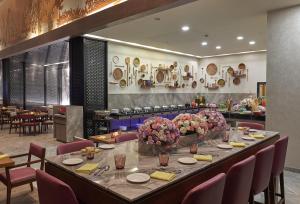 加尔各答Vivanta Kolkata EM Bypass的用餐室配有带鲜花的长桌