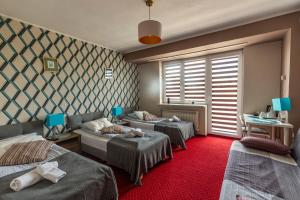 华沙卡瓦别墅酒店的一间设有三张床的客房,铺有红地毯