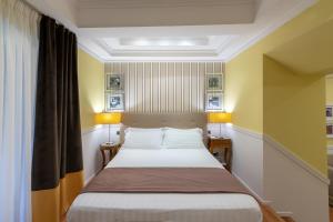 那不勒斯图尔基尼宫酒店的黄色墙壁和两盏灯的房间的一张床位