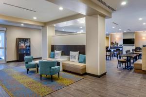 大瀑布城MainStay Suites Great Falls Airport的一间设有桌椅的等候室和一间酒吧
