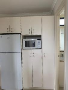 阿波罗湾Beach Cabin Apollo Bay的白色的厨房配备了微波炉和冰箱。