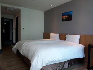 桃园市福昇商旅的卧室配有一张白色大床,墙上挂着一幅画