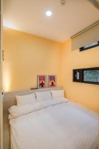 鱼池乡貓頭鷹旅店的一张白色的大床,位于拥有黄色墙壁的房间