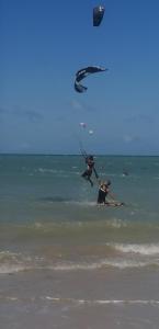 卡姆布库CASA MEUS AMIGOS KITESURF in the center of Cumbuco的两个人在海洋里玩风筝