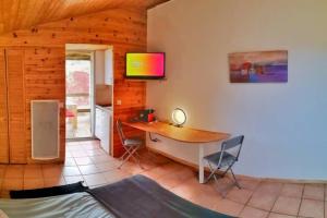 LiaussonStudio 22 m2, terrasse vue lac, dans propriété face au Lac du Salagou的客房设有书桌和墙上的电视。