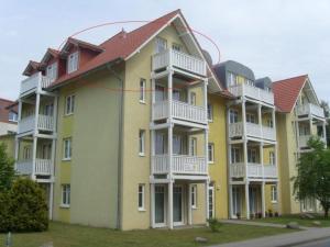 奥斯赛拜-屈隆斯博恩Strandschloesschen-Haus-II-WE-20-9720的大型黄色公寓大楼设有白色阳台