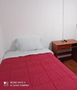 库里科Hospedaje curicó casa grande的一张带红色毯子的床和一张书桌