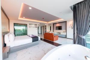 北芭堤雅The Proud Hotel Pattaya - SHA Certified的一间卧室配有一张床、一张沙发和一台电视