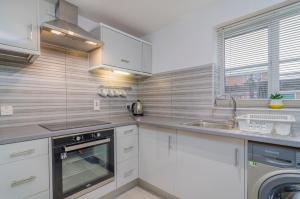 ThamesmeadKentmere Apartment Thamesmead的厨房配有白色橱柜、水槽和洗碗机。