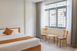 头顿Anh Đào Hotel的一间卧室配有一张床、两把椅子和一个窗户