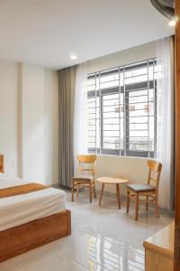 头顿Anh Đào Hotel的一间卧室配有一张床、两把椅子和一张桌子