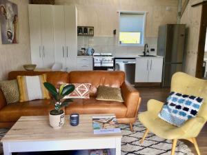 沃克沃思Warkworth Barn Retreat的一间带棕色真皮沙发的客厅和一间厨房