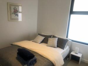 卡尔斯C-Scape Penthouse - Cowes beach front的卧室配有带枕头的床铺和窗户。