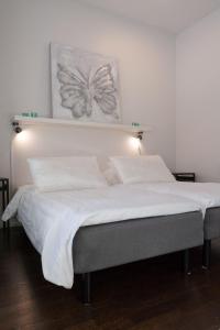 于韦斯屈莱Apartment Lumikontupa的一张铺有白色床单的床和墙上的蝴蝶照片