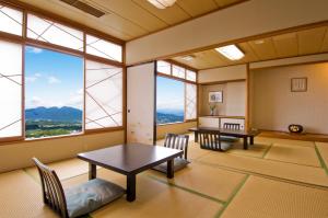 涩川市伊香保秀水园日式旅馆的配有2张桌子和椅子以及大窗户的客房