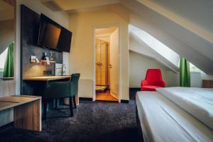 班贝格欧罗巴酒店的一间卧室配有一张床、一张桌子和一把红色椅子