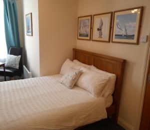 达特茅斯Foss Room的一间卧室配有一张铺有白色床单的床,墙上挂有图片