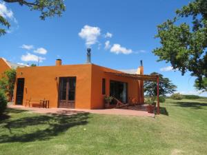 科洛尼亚-德尔萨克拉门托Estancia San Pedro的一座橙色的小房子,前面有草坪