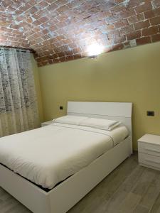 卡萨莱蒙费拉托Residenza Nikol的砖墙房间内的一张白色床