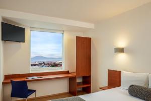 普埃布拉万普布拉芬撒酒店的客房设有床、书桌和窗户。