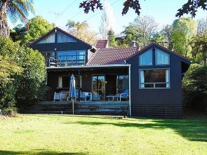 Okere FallsLakeside Villa - Lake Rotoiti Holiday Home的草坪上带天井和遮阳伞的房子