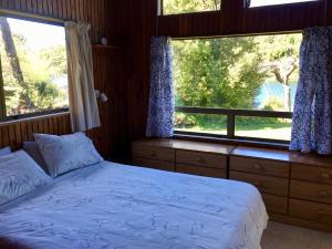 Okere FallsLakeside Villa - Lake Rotoiti Holiday Home的一间卧室设有一张床和两个窗户。