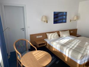 斯图加特Mirage City Hotel Stuttgart Zentrum的卧室配有1张床、1张桌子和1把椅子