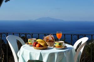阿纳卡普里Le Ginestre di Capri BB & Holiday House的一张桌子,上面放着一碗水果和一杯果汁