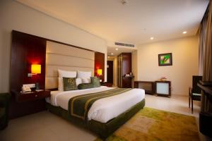 拉合尔Nine Tree Luxury Hotel & Suites Lahore的酒店客房设有一张大床和一台电视。