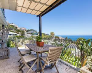 开普敦Villa del Mar - "Luxurious en-suite bedroom with lounge and stunning sea view balcony in Bantry Bay"的阳台上的木桌和椅子