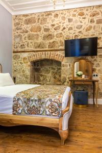 安塔利亚Hotel Lykia Old Town Antalya的一间卧室设有一张床,石墙上配有电视。