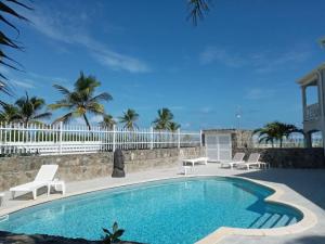 东方湾Princess Coco, Beachfront, Pool, Orient Bay, ultra fast Wifi的一个带椅子和白色围栏的游泳池