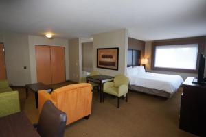 坎宁维尔Creekside Hotel & Suites的酒店客房,配有一张床、一张桌子和椅子